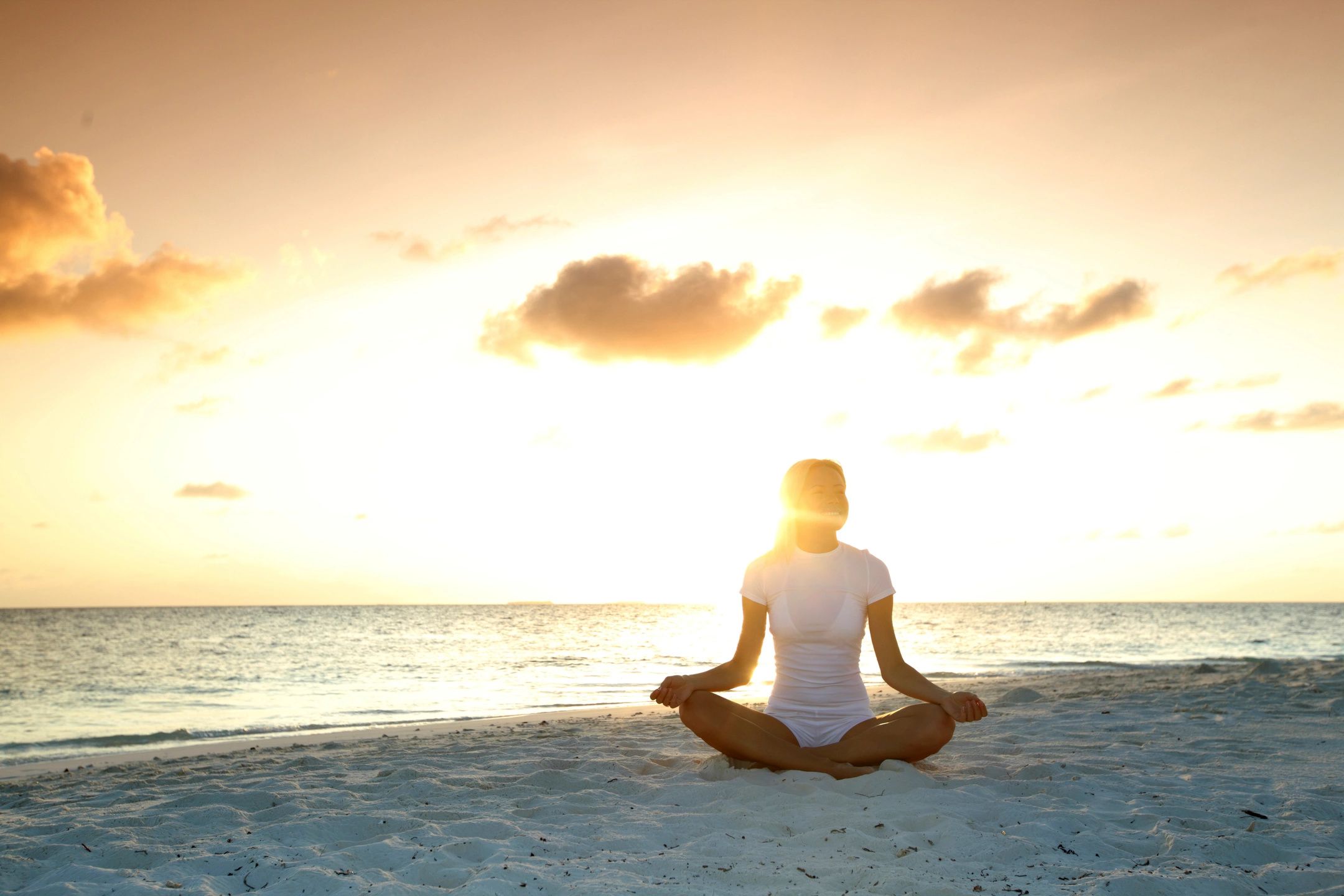 A woman sitting on the beach in front of the ocean.